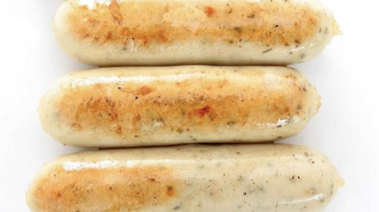 Three chicken sausages on white background