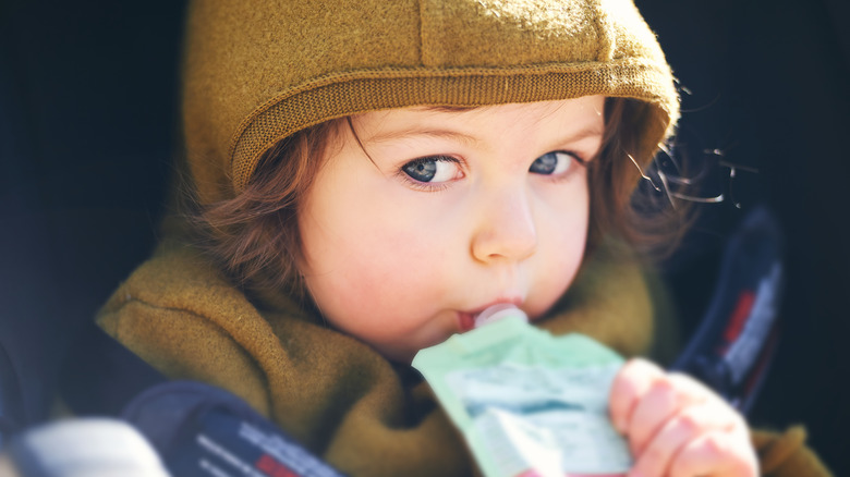 Young child drinking fruit purée pouch