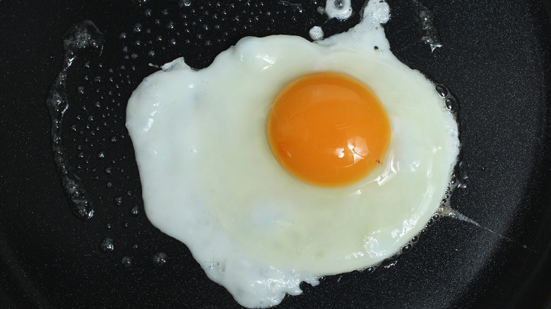 Egg frying in black pan