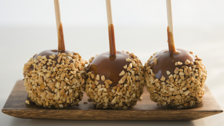 Three caramel apples covered in nuts