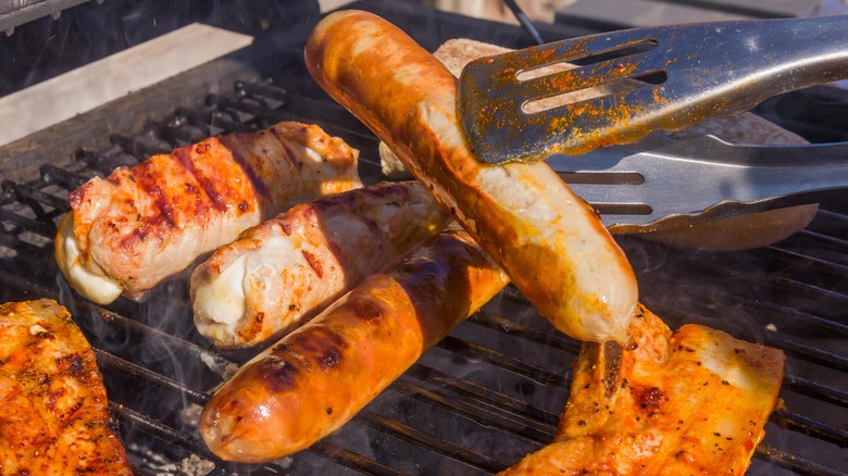 Person flips sausages on grill