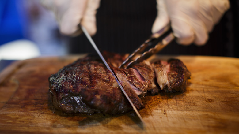 Person carves grilled steak