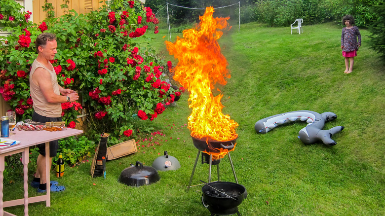 Man and girl watch grill fire