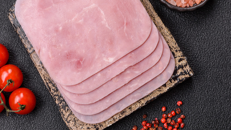 Sliced ham next to tomatoes and berries