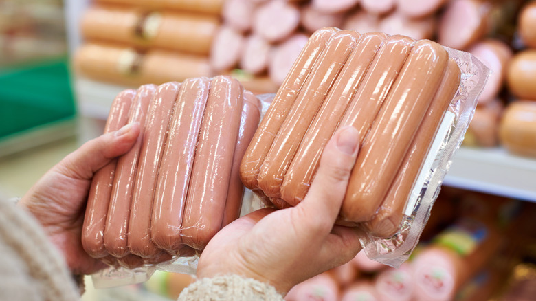 shopper holding packs of hot dogs