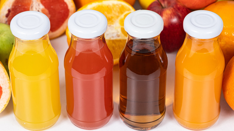 Fruit juices in glass bottles with fruit background