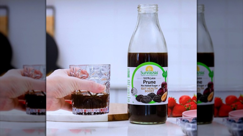 Sunraysia prune juice with hand holding glass