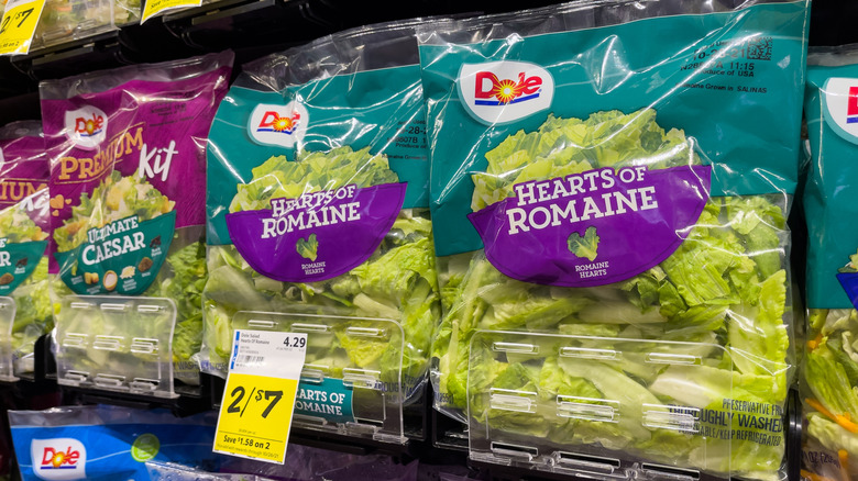 Bags of Dole romaine lettuce on grocery store shelf