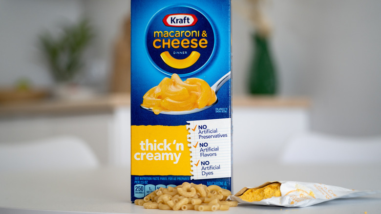 Kraft macaroni and cheese box with dried noodles and a cheese package below