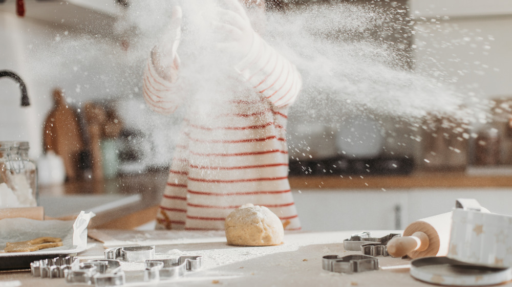 Child having fun cooking, making mess with flour