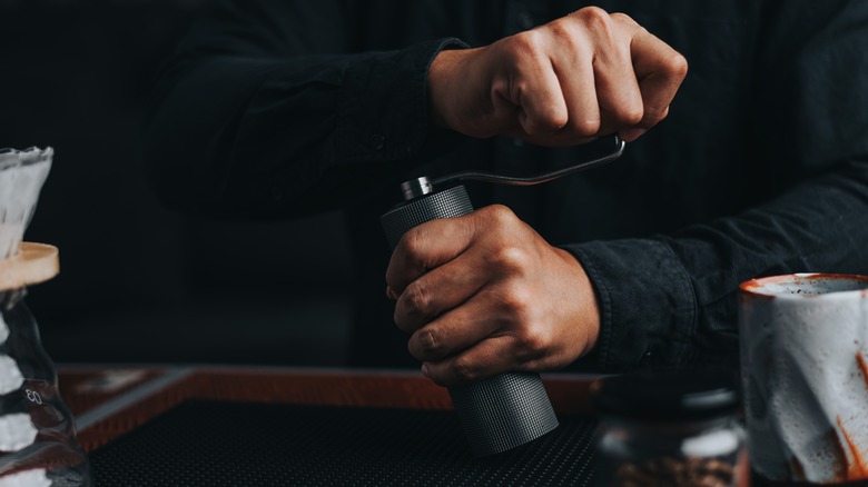 Hands grinding coffee manually