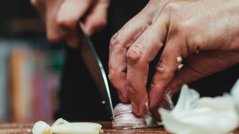 close up of a chef knife cutting a shallot