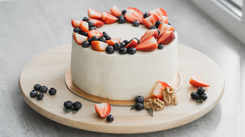 round cake with white frosting, strawberries, and blueberries