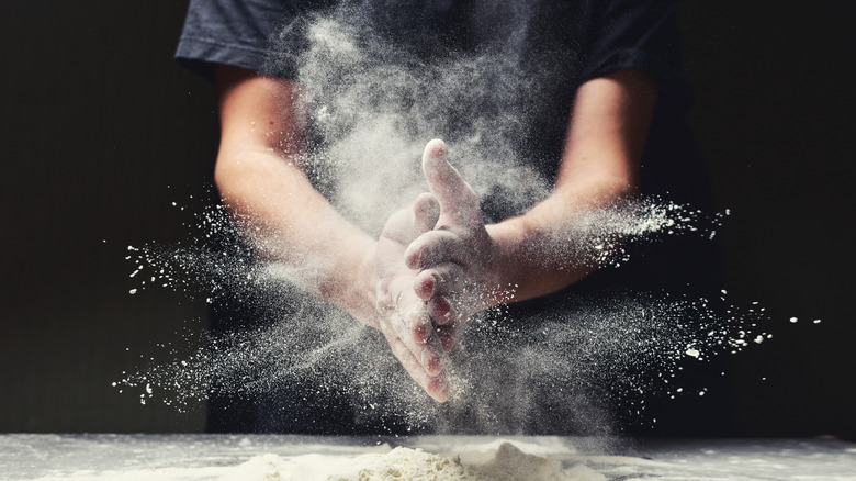 Cook clapping his hands to shake off flour