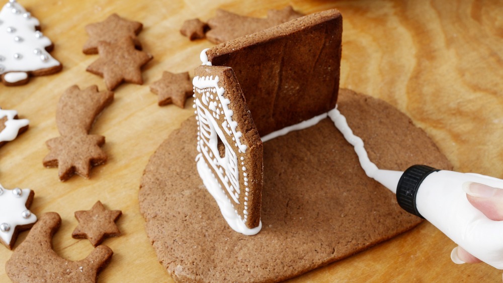 woman constructing a gingerbread house