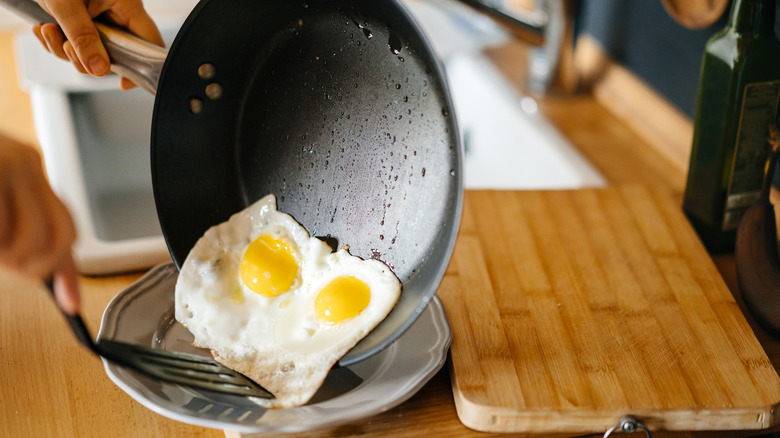 Eggs fried in nonstick pan being put on plate