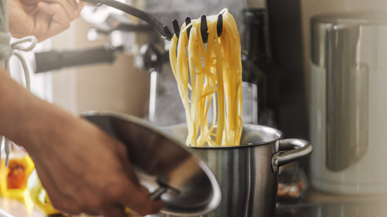 scooping cooking spaghetti from pot