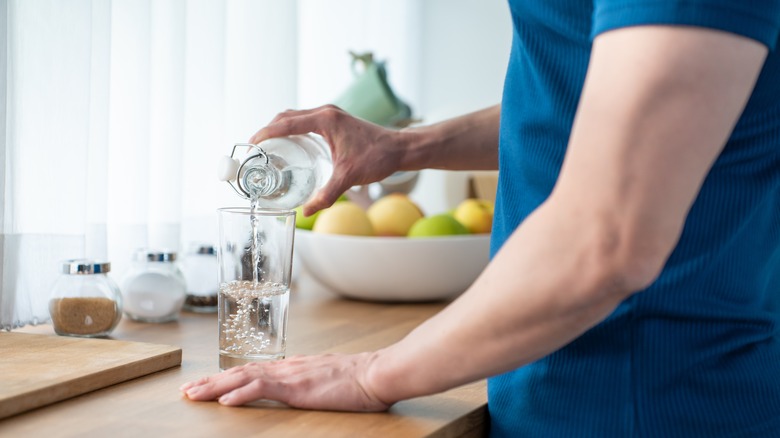 Person pouring water from jug into cup