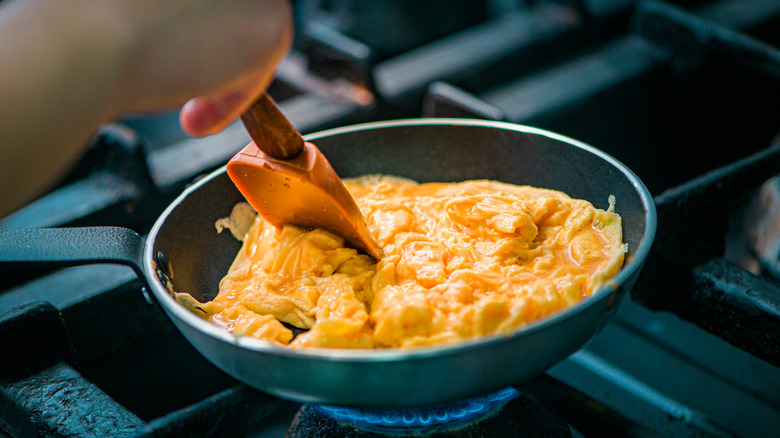 Rubber spatula scrambling eggs in a pan