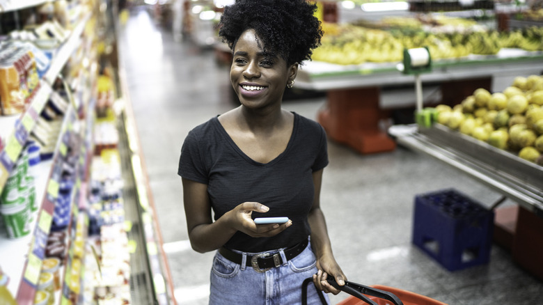 woman checking phone in grocery store