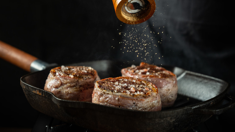 seasoning steak in skillet