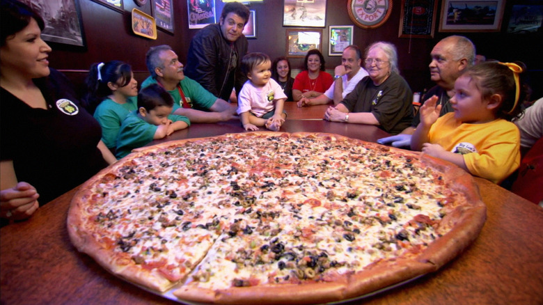 chef's family surrounding giant pizza