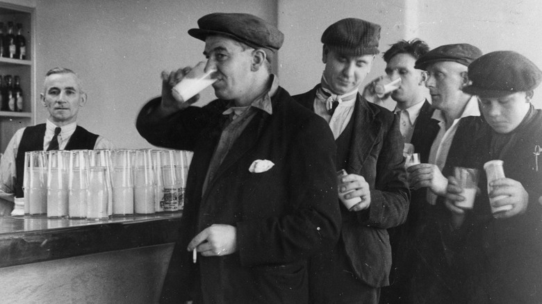 men drinking glasses of milk in black and white photo