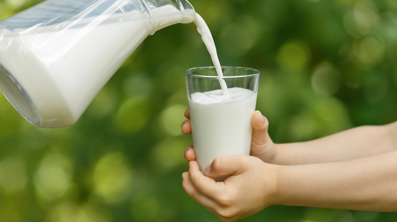 milk pouring into a glass held by a child