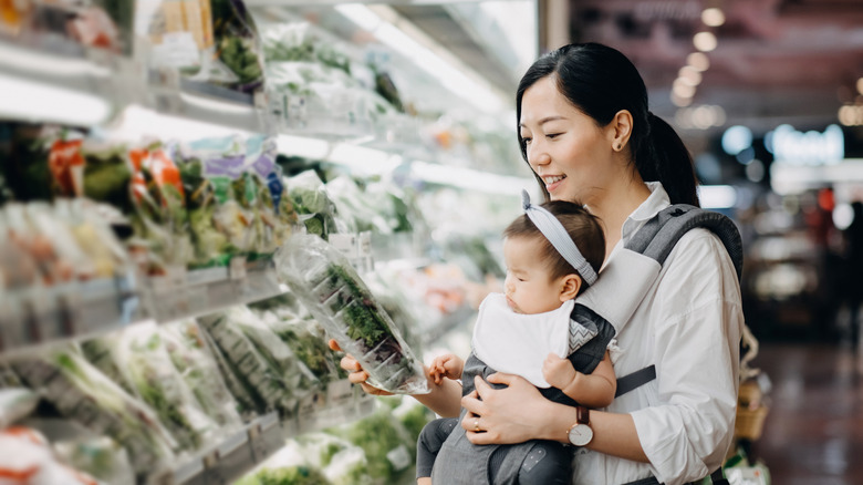 Woman with baby holding packaged salad