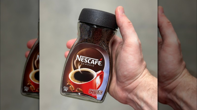 Hand holding jar of Nescafé Classic coffee