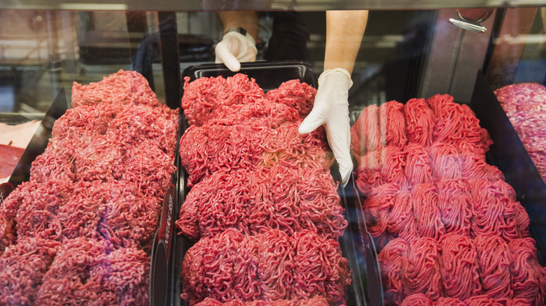 Hand touching piles of ground beef