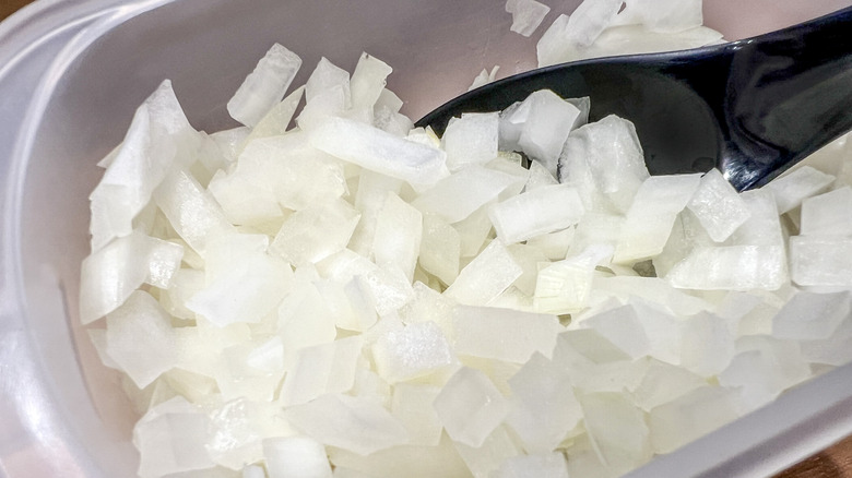 closeup of diced onions in bowl with black spoon