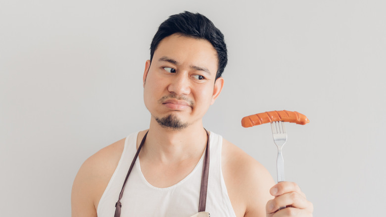 Person looking at sausage with suspicion