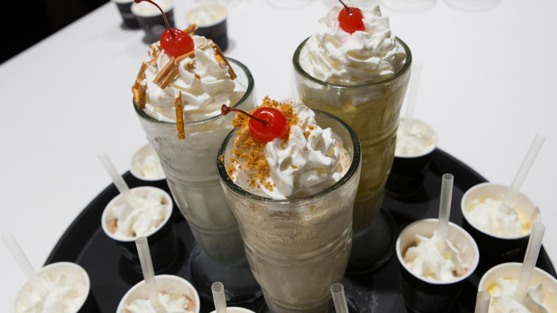 Three milkshakes whipped cream maraschino cherries