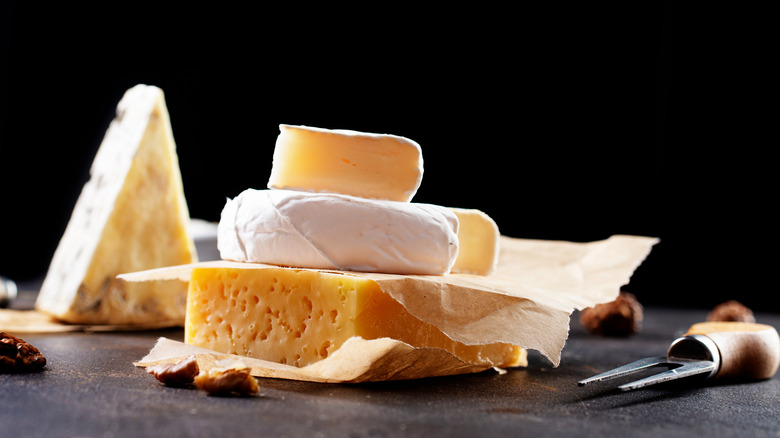 An assortment of cheeses next to a cheese fork