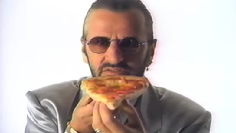 Ringo Starr holding a slice of stuffed crust pizza