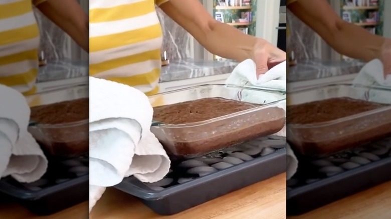 Hand holding a brownie pan over a tray of ice