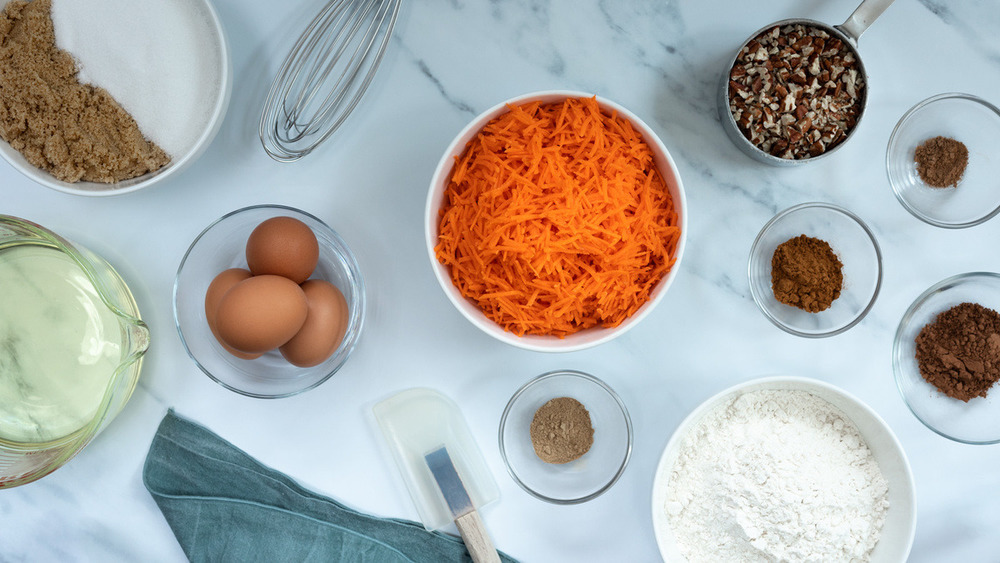 Carrots, eggs, flour, sugars, spices, oil in bowls on counter