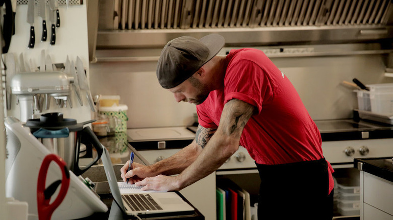 Chef Dave White writing in kitchen
