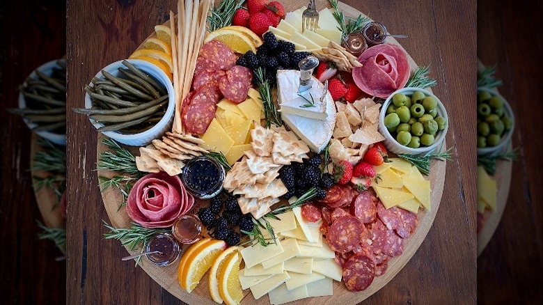 A charcuterie board with meat, cheese, fruit and nuts