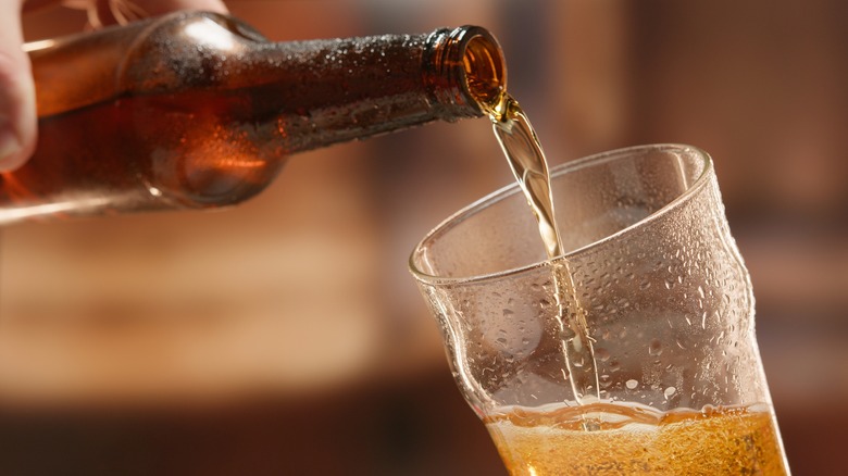 beer being poured in a glass with hand