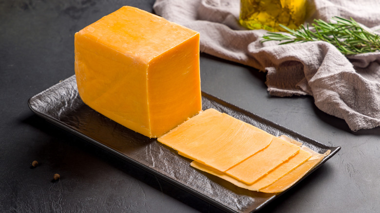 cheddar in slices on wood board with napkin