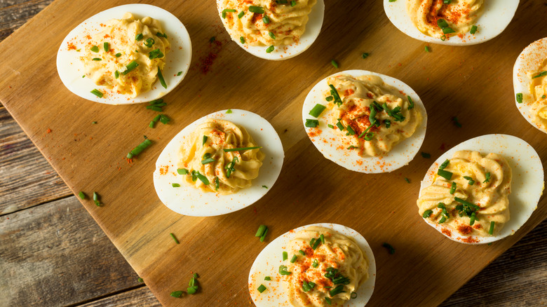 deviled eggs with chives on wooden board