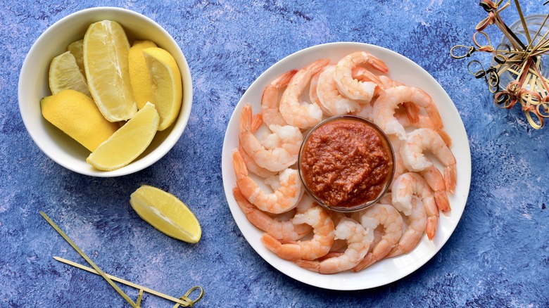 shrimp cocktail in plate with lemon wedges