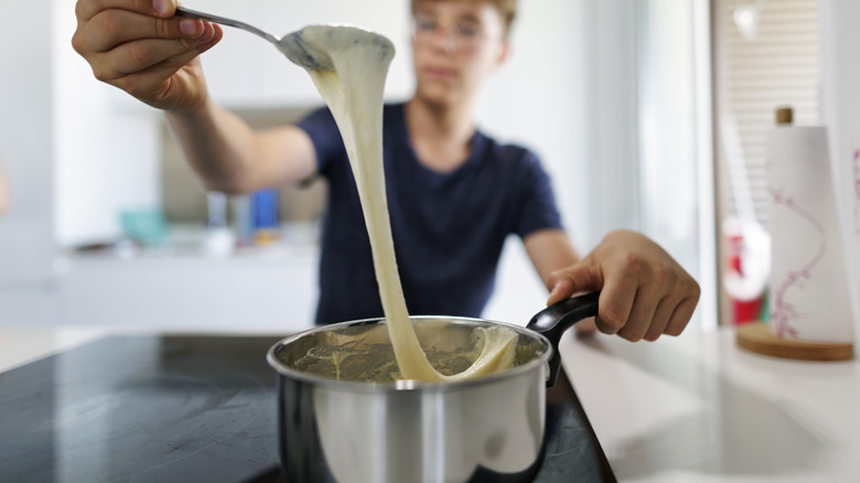 person melting cheese in a pot