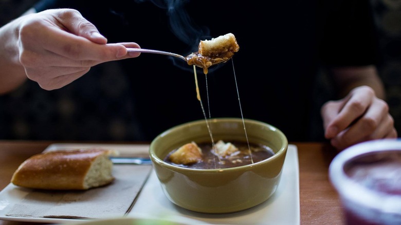 hands spooning Panera French onion soup