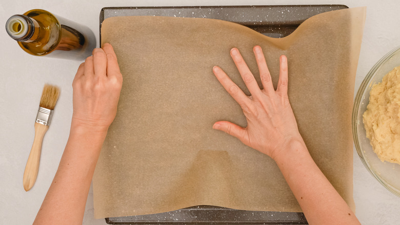 hands lining pan with parchment paper 