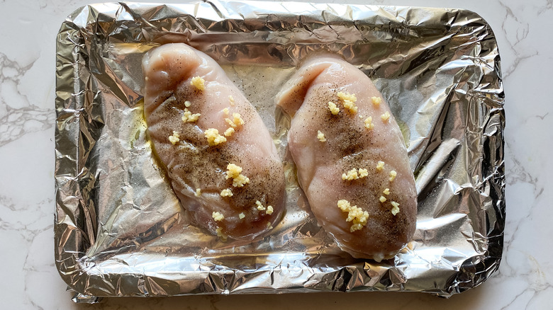 Raw chicken on a foiled baking sheet 