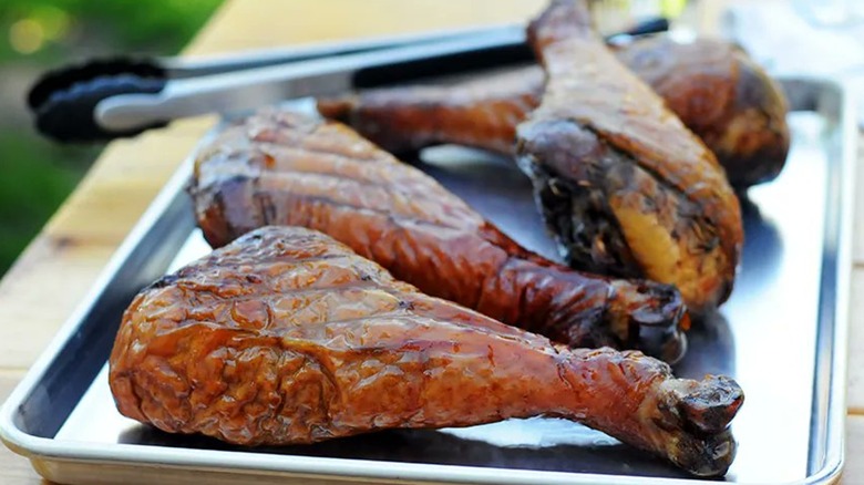 Andrew Zimmern's smoked turkey legs on a metal sheet tray with tongs