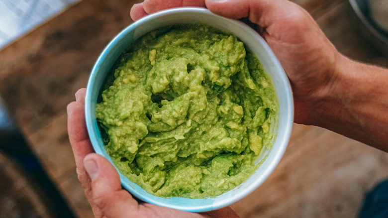 hands holding guacamole bowl